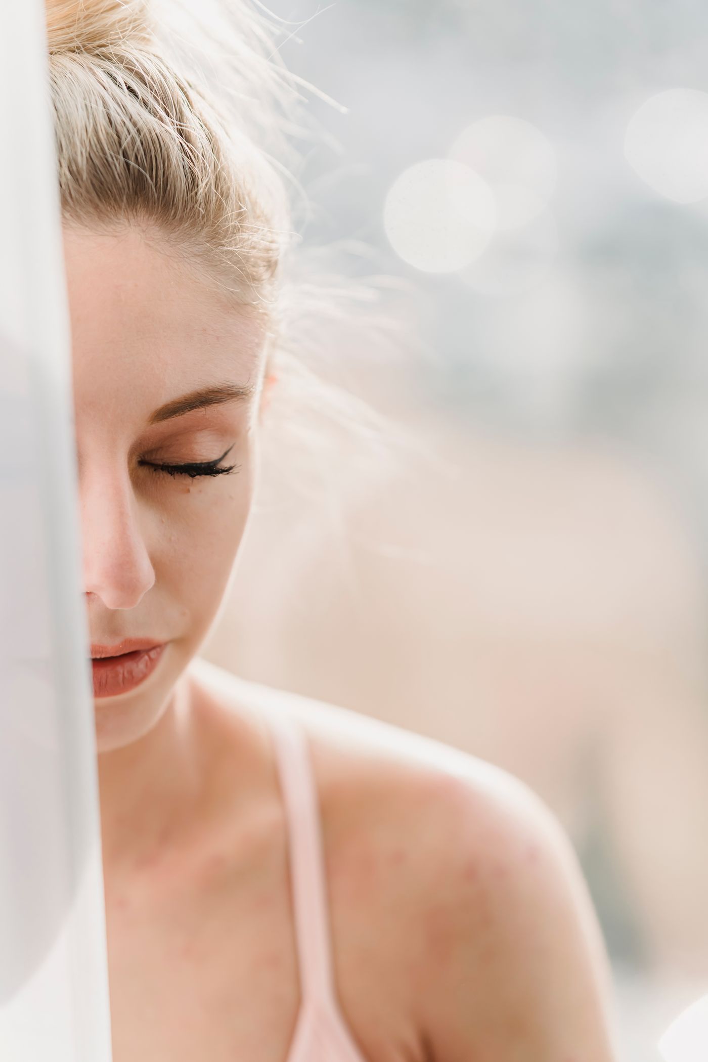 Frau sitzt mit geschlossenen Augen auf einem sonnigen Fensterbrett und macht eine Atempause.